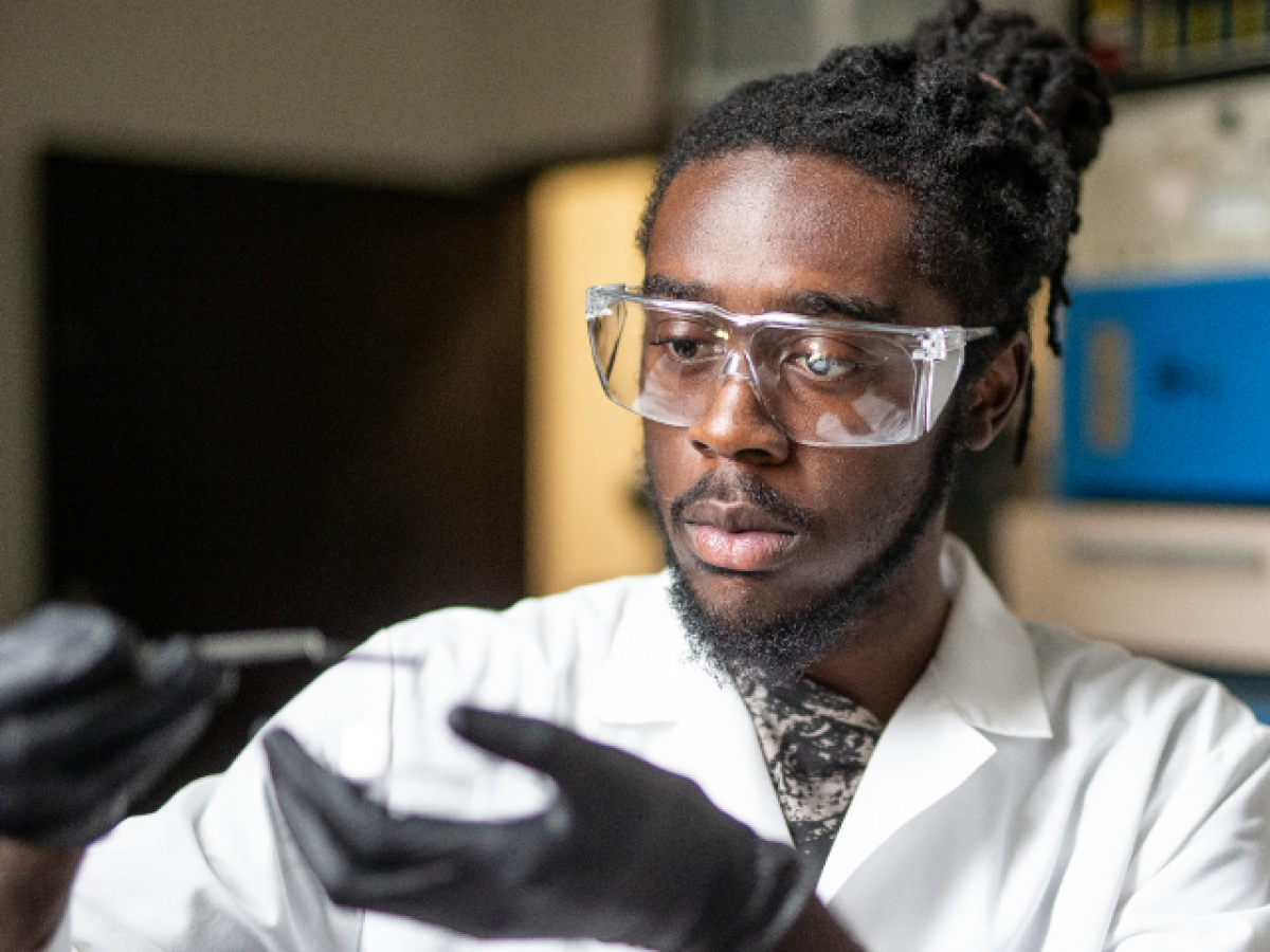 student wearing goggles, holding an object